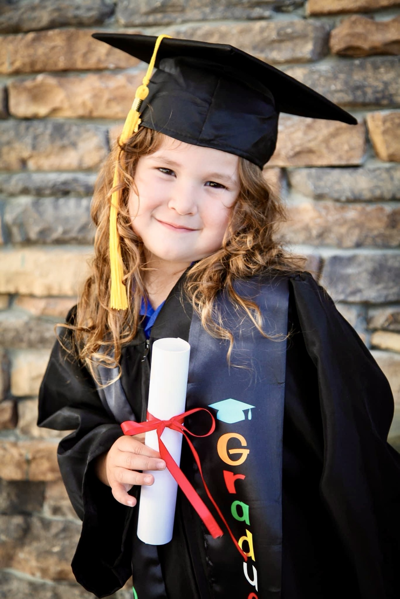 VPK graduate in cap and gown holding her diploma